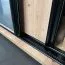Schiebetürenschrank Mina 1,1 Meter breit in Weiß/Eiche, Front aus laminierter Platte, Anti Staubbürsten, schwarze Lamellen Optik, Metallgriffe in schwarz